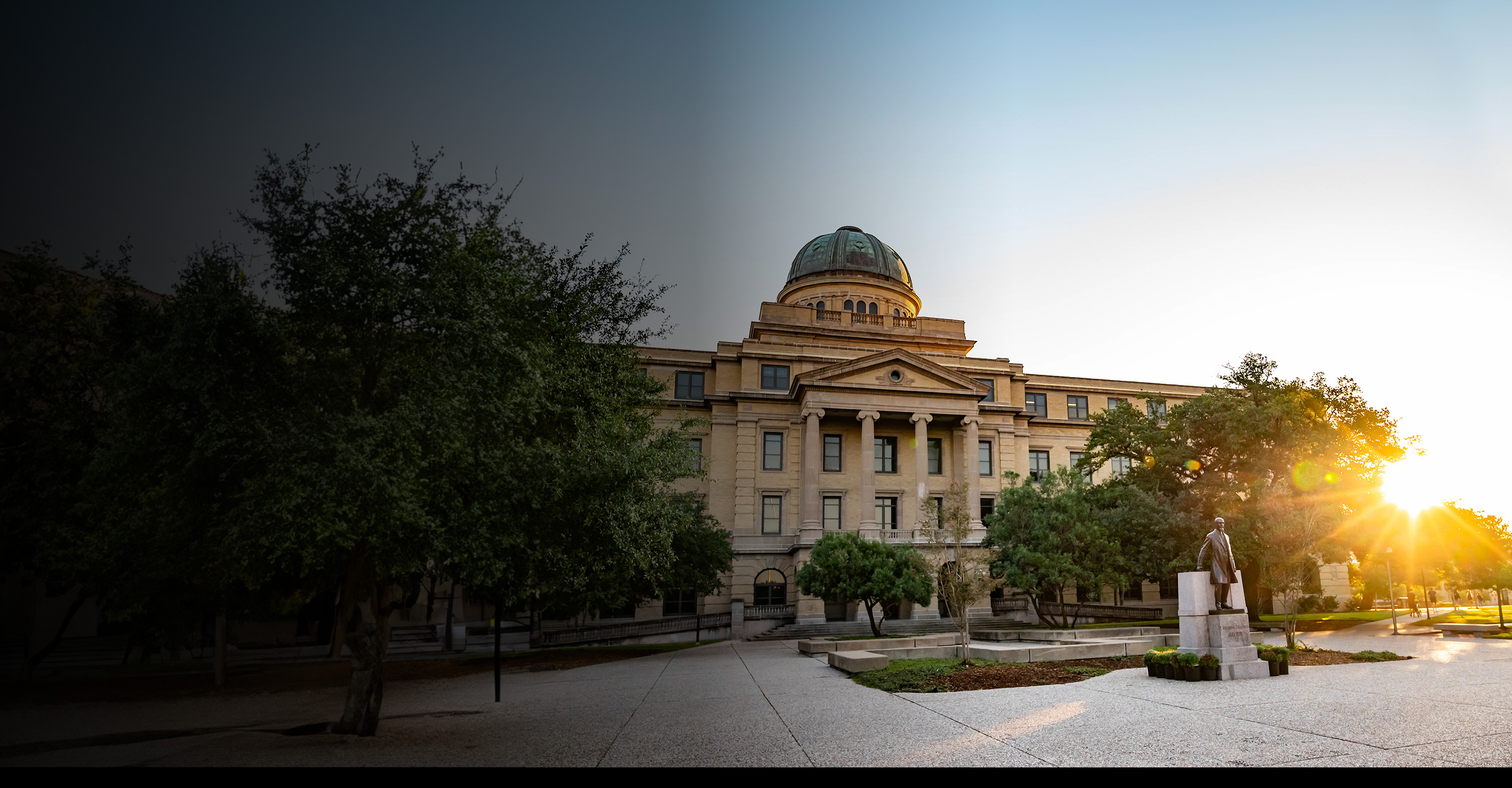 academic building with dome roof and statue in front during sunset