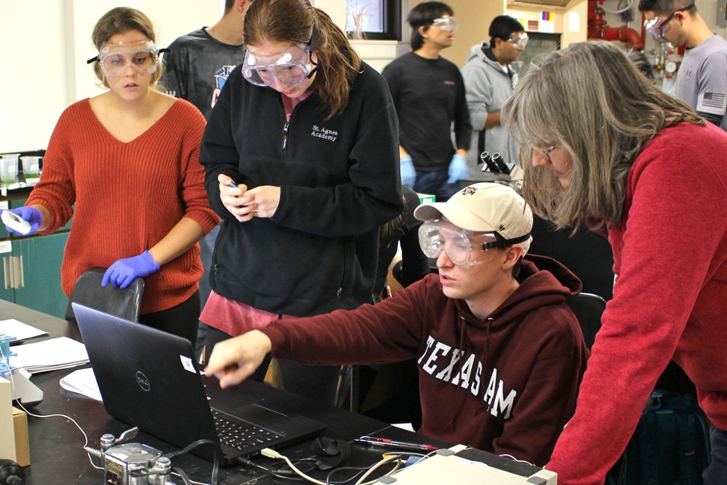 Students work in a group to discuss results found on the computer as a professor monitors.