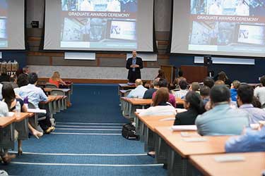 A man giving a lecture in front a large group of students