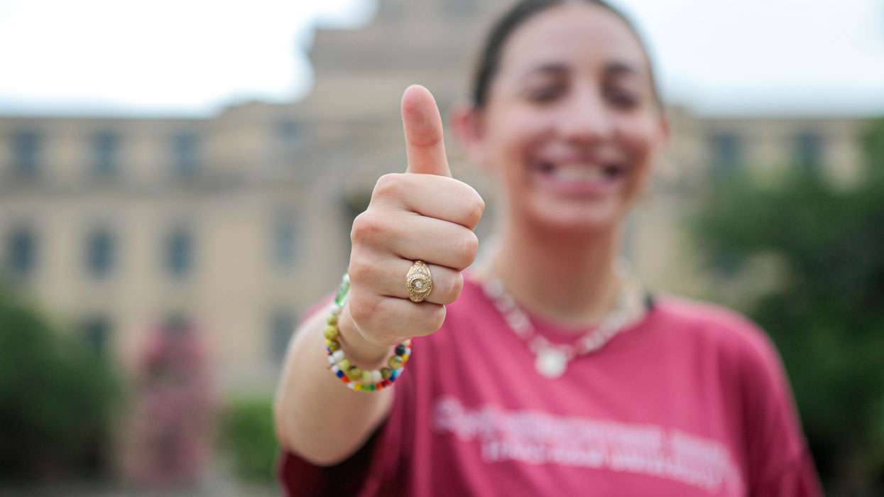 Student holding a gigem thumbs up