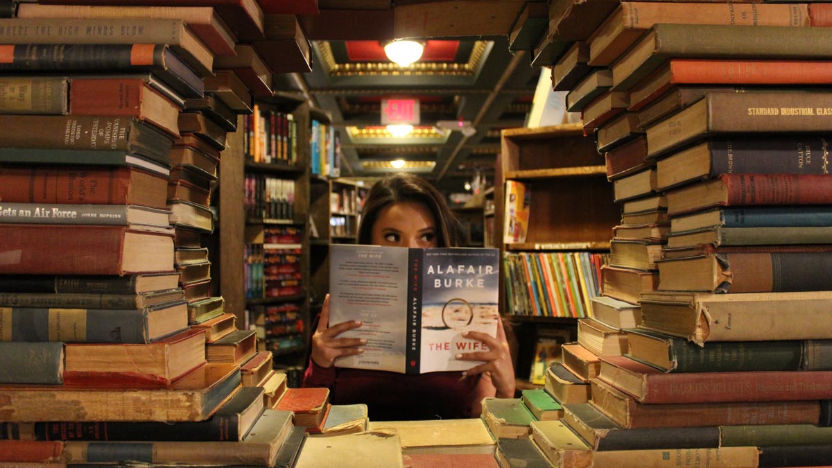 Female reader in a library surround by stacks of books