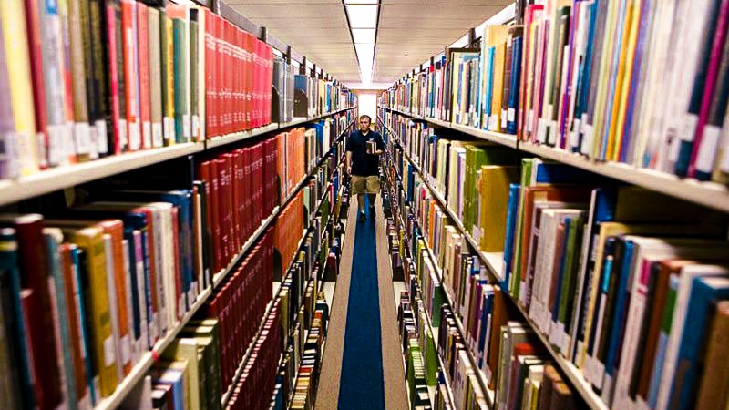 Male student walking through library stacks