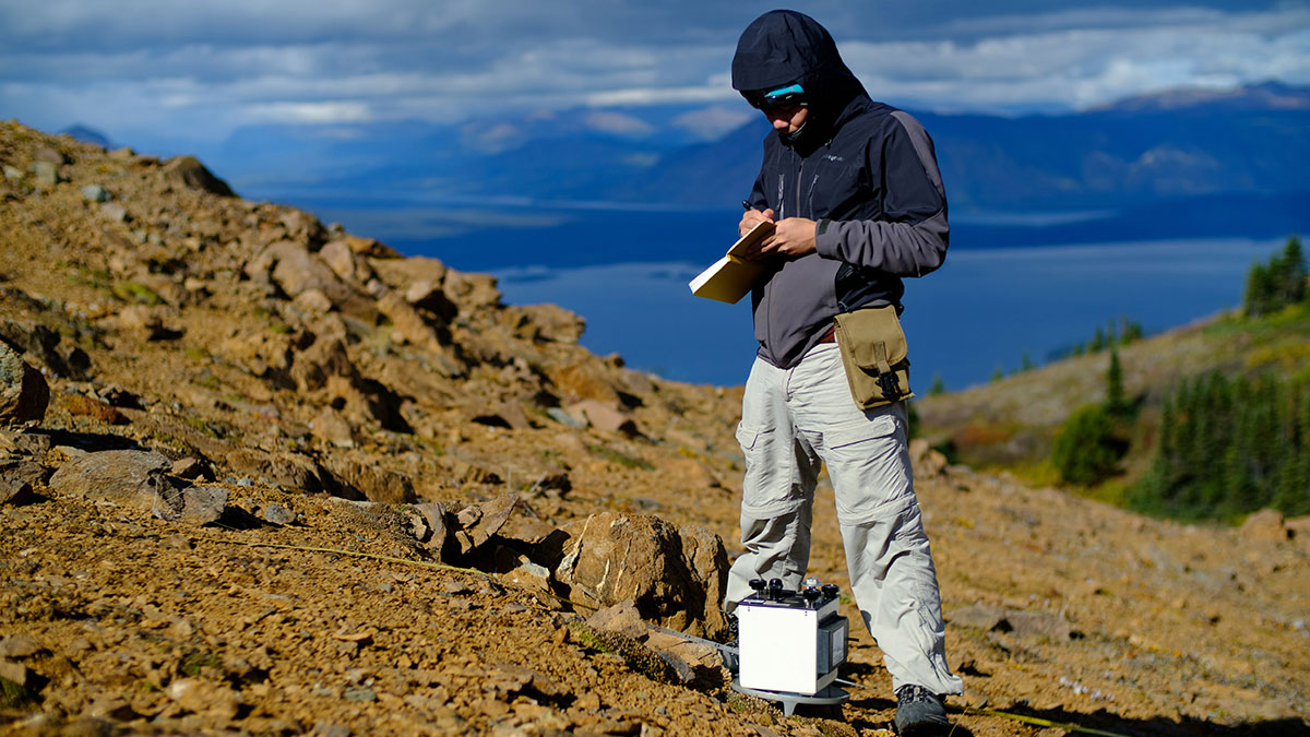 Male student recording research data while standing near research equipment