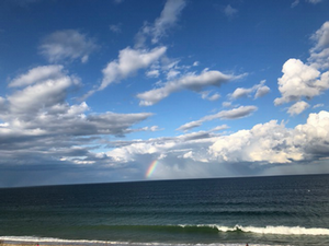 Calm sea with distant rainbow on horizon