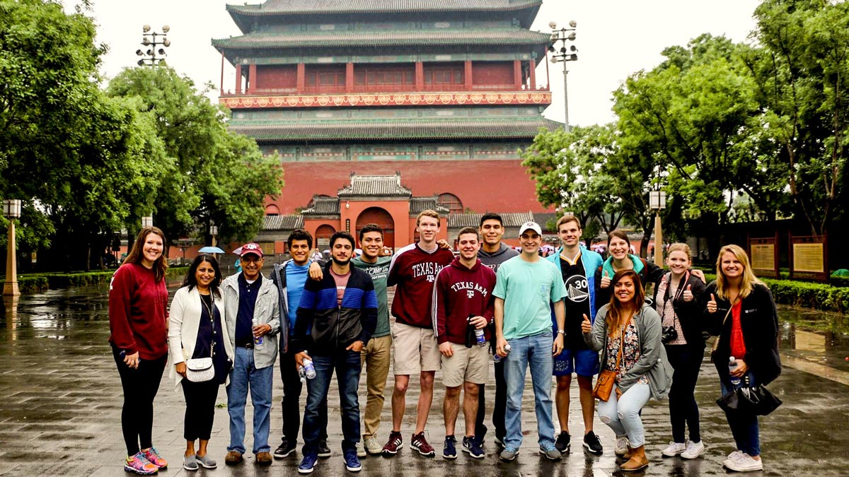 Diverse group of students posing in front of Asian architecture