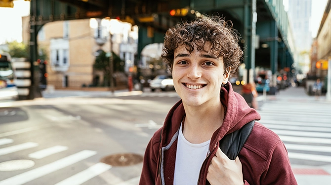 Young male student with backpack standing under elevated roadway