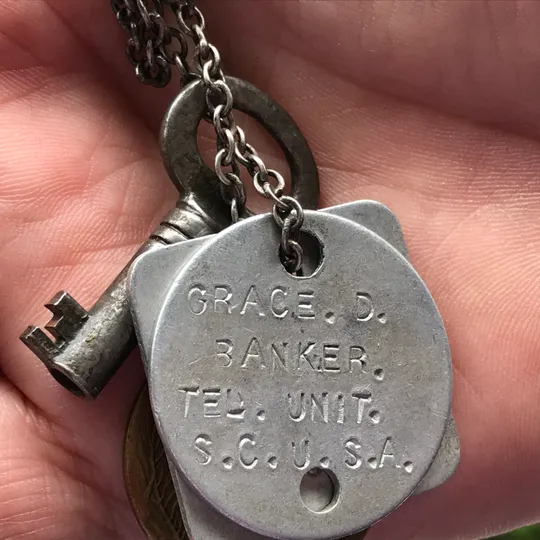 An old silver dog tag engraved with, "Grace D. Banker Ted Unit S.C.U.S.A."