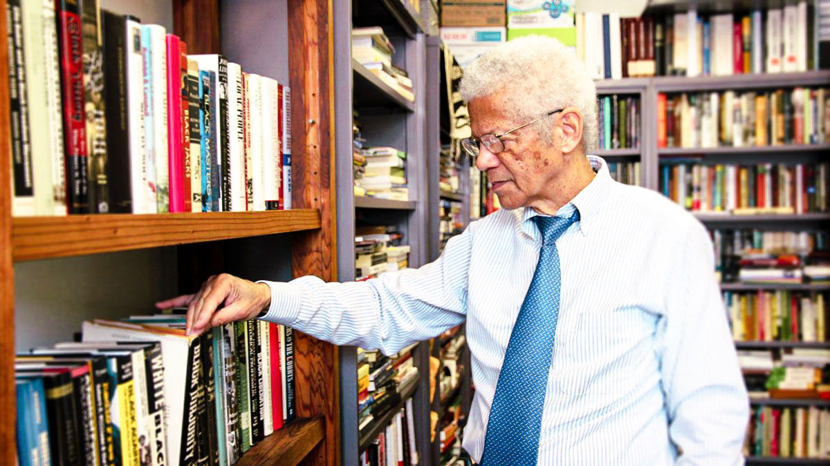 An older gentleman in the library sifting through books
