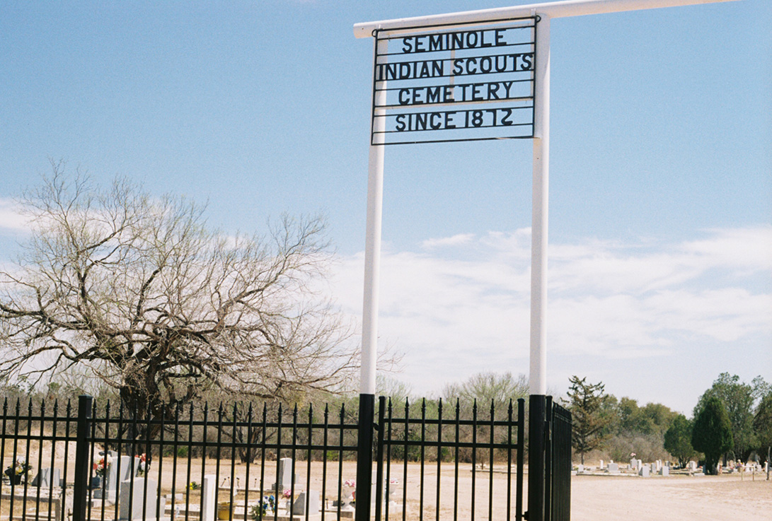 photo of cemetery on sunny blue sky day with steel sign that reads Seminole Scout Cemetery