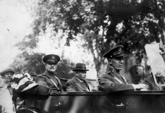 General John J. Pershing, Robert Dix Benson, and Lieutenant George Marshall riding in a convertible town-car during a parade.
