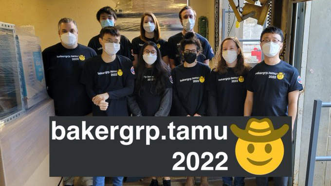 A group of individuals representing, The Baker Group, posing in a hallway, holding a banner that reads bakergrp.tamu 2022
