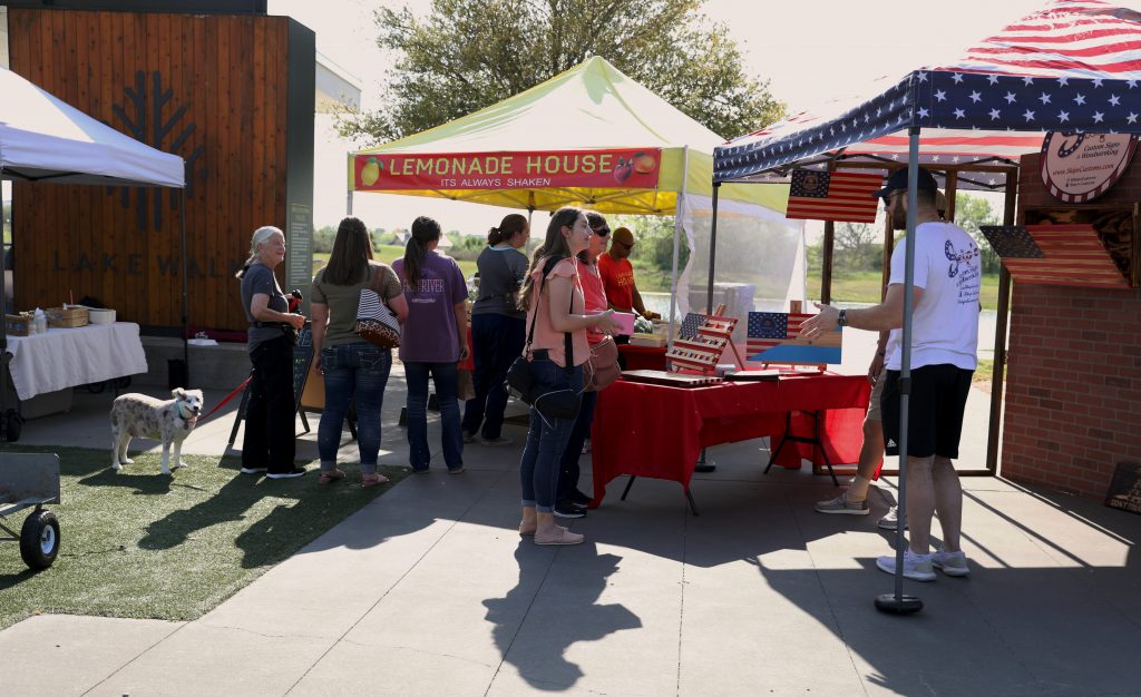 People standing in line at a "Lemonade House" tent and American flag tent