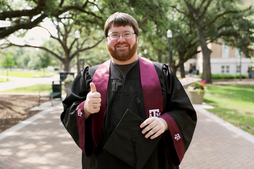 Brady Stone in graduation gown giving the gig'em sign