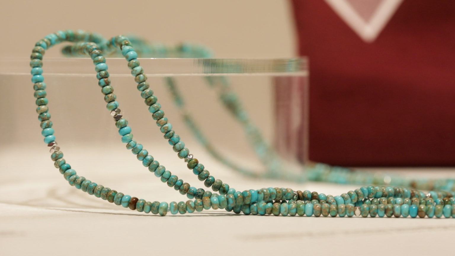 Several strands of turquoise beads on a transparent pedestal