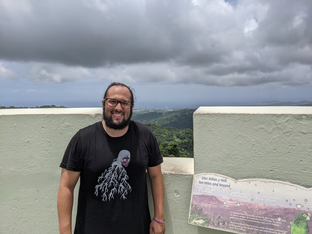 Ian Seavey standing next to a marker overlooking Puerto Rico