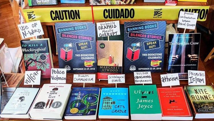 Table display of banned books with "Caution" tape around it