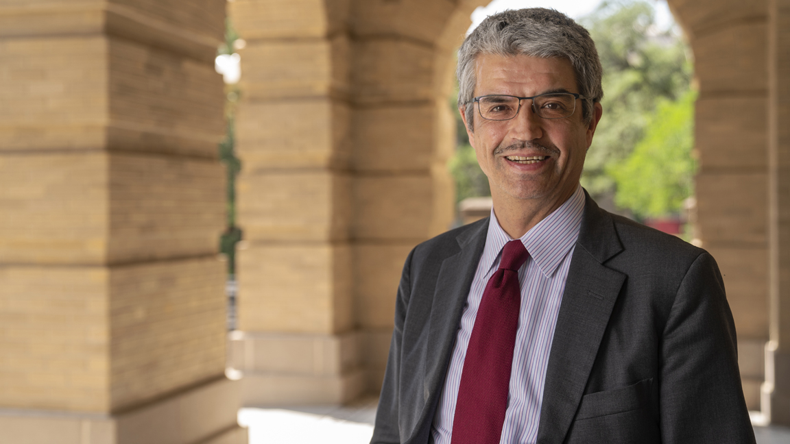 Dr. José Luis Bermúdez, Interim Dean of the College of Arts and Sciences, Professor of Philosophy and the Samuel Rhea Gammon Professor of Liberal Arts at Texas A&amp;M University, smiles while posing in the archways of the Academic Building while wearing a gray suit and maroon tie