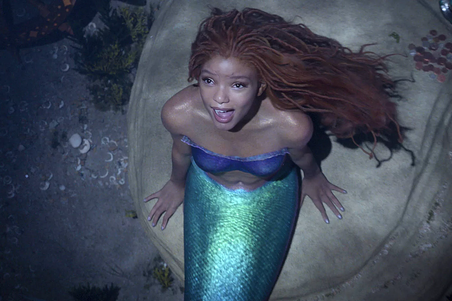 Actress Halle Bailey sits on a boulder dressed as a mermaid