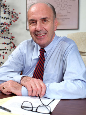 Ian Scott pictured sitting at a desk with his glasses before him