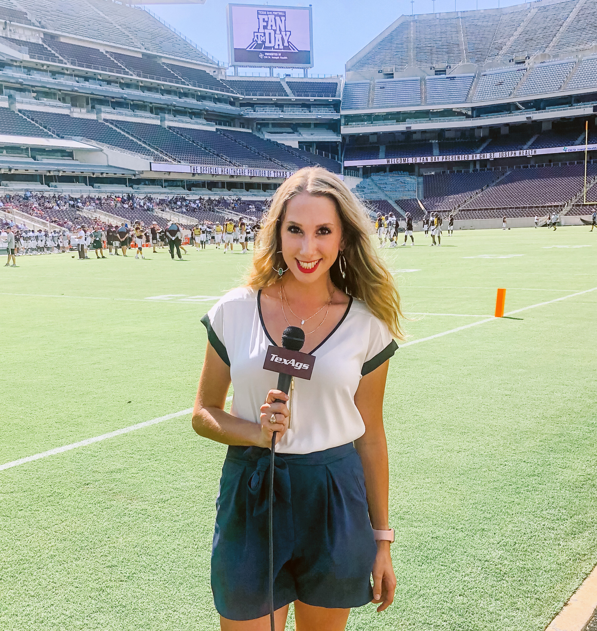 2019 Texas A&amp;M telecommunications graduate Lia Musgrave holds a TexAgs microphone while reporting from the sidelines of Kyle Field at Texas A&amp;M Football Fan Day