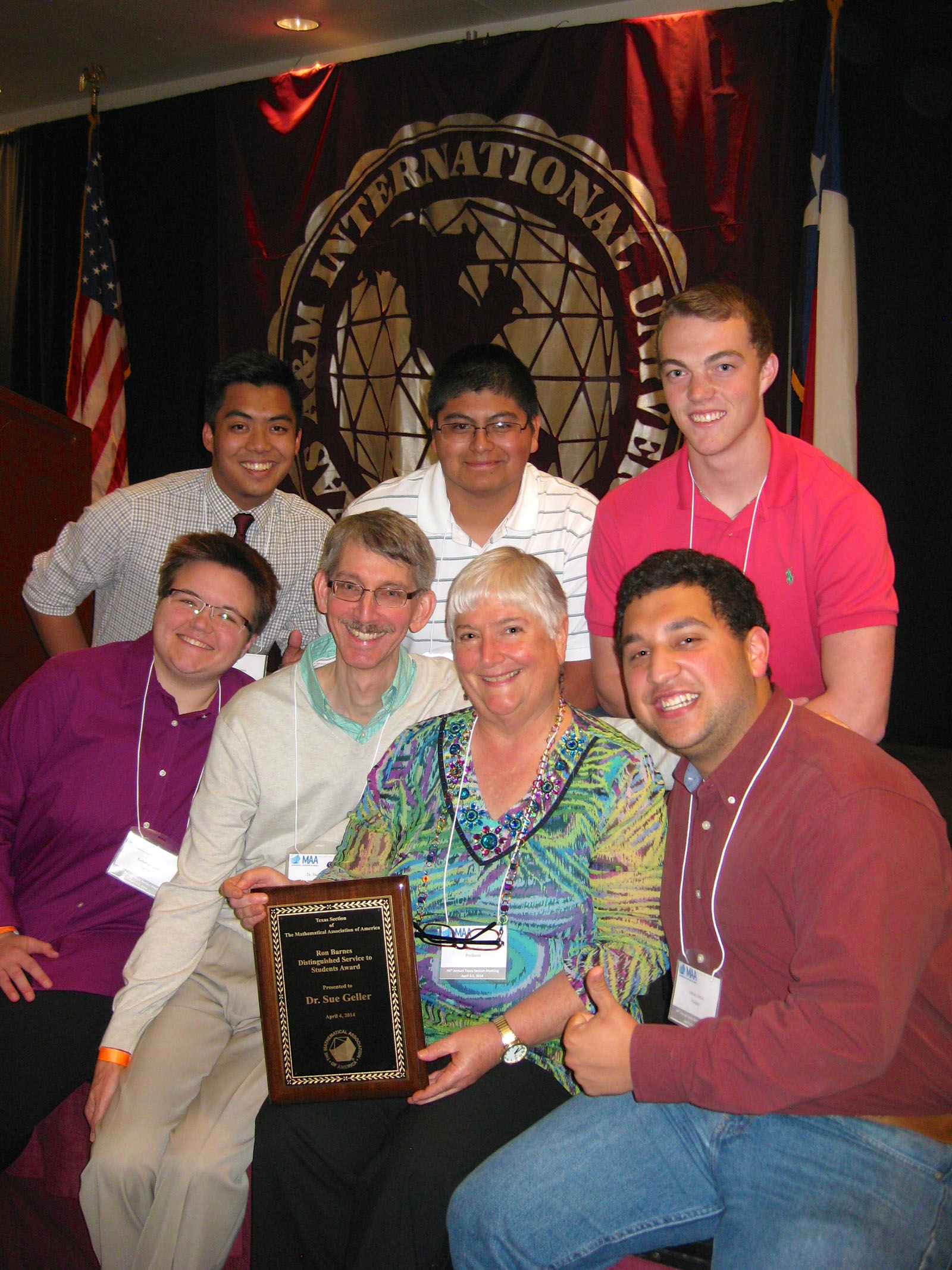 Texas A&amp;M mathematician Sue Geller holds a plaque surrounded by fellow faculty and her math students