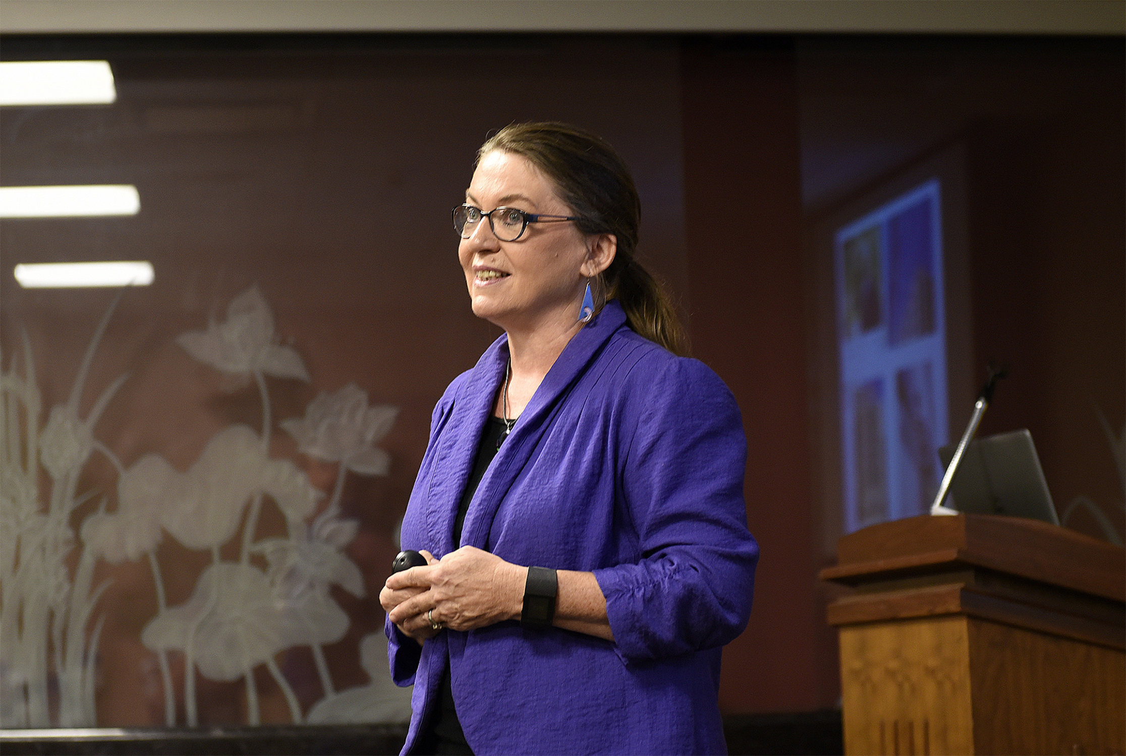 Texas A&amp;M biologist Deborah Bell Pedersen stands in front of a podium and speaks to an audience