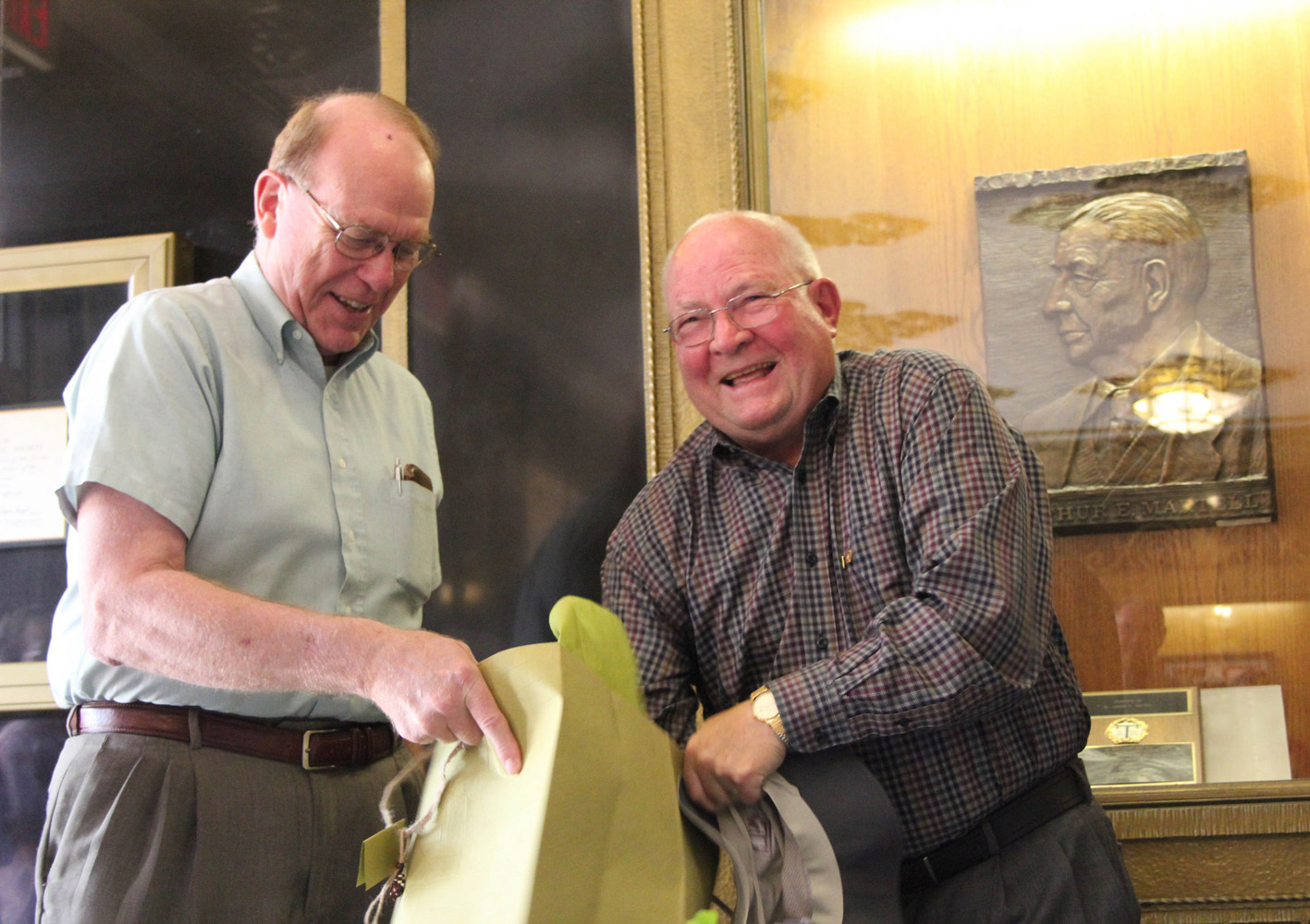 Texas A&amp;M chemist Michael Rosynek (left) looks on as fellow Texas A&amp;M chemist John Fackler (right) opens a gift at his 80th birthday celebration in the Texas A&amp;M Chemistry Building.