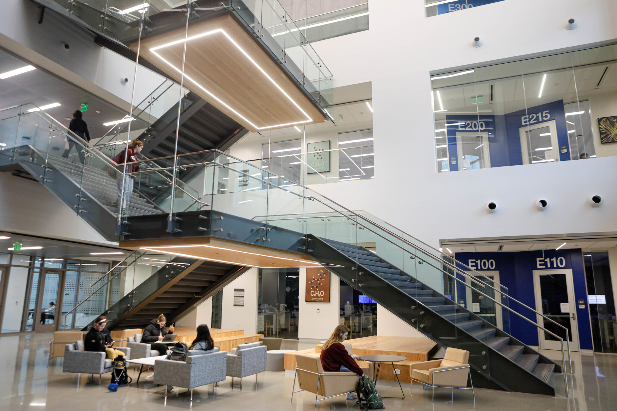Interior view of the Instructional Laboratory and Innovative Learning Building at Texas A&amp;M University featuring students seated in the foyer, a two-way staircase, and partial views of the building’s first two floors