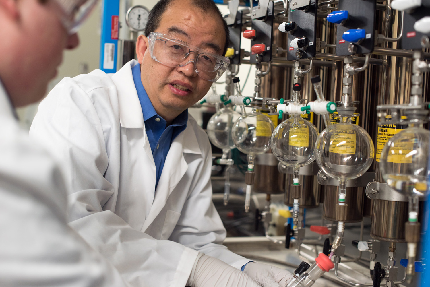 Texas A&M chemist Hongcai Joe Zhou instructs a student as he fills glassware in his lab