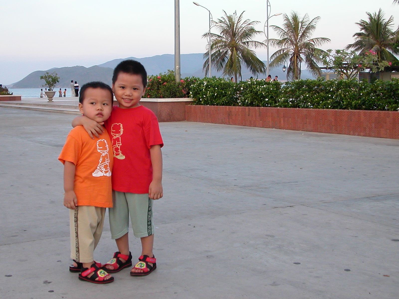 Henry and Kyle Nguyen, who has one arm draped over his brother's shoulder, standing on a pier as young children