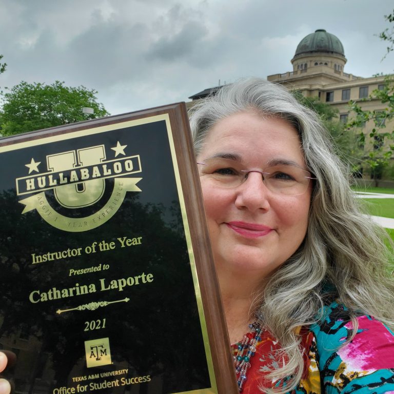 Texas A&amp;M anthropologist Catharina Laporte poses with her Hullabaloo U Instructor of the Year award plaque with the Academic Building in the background