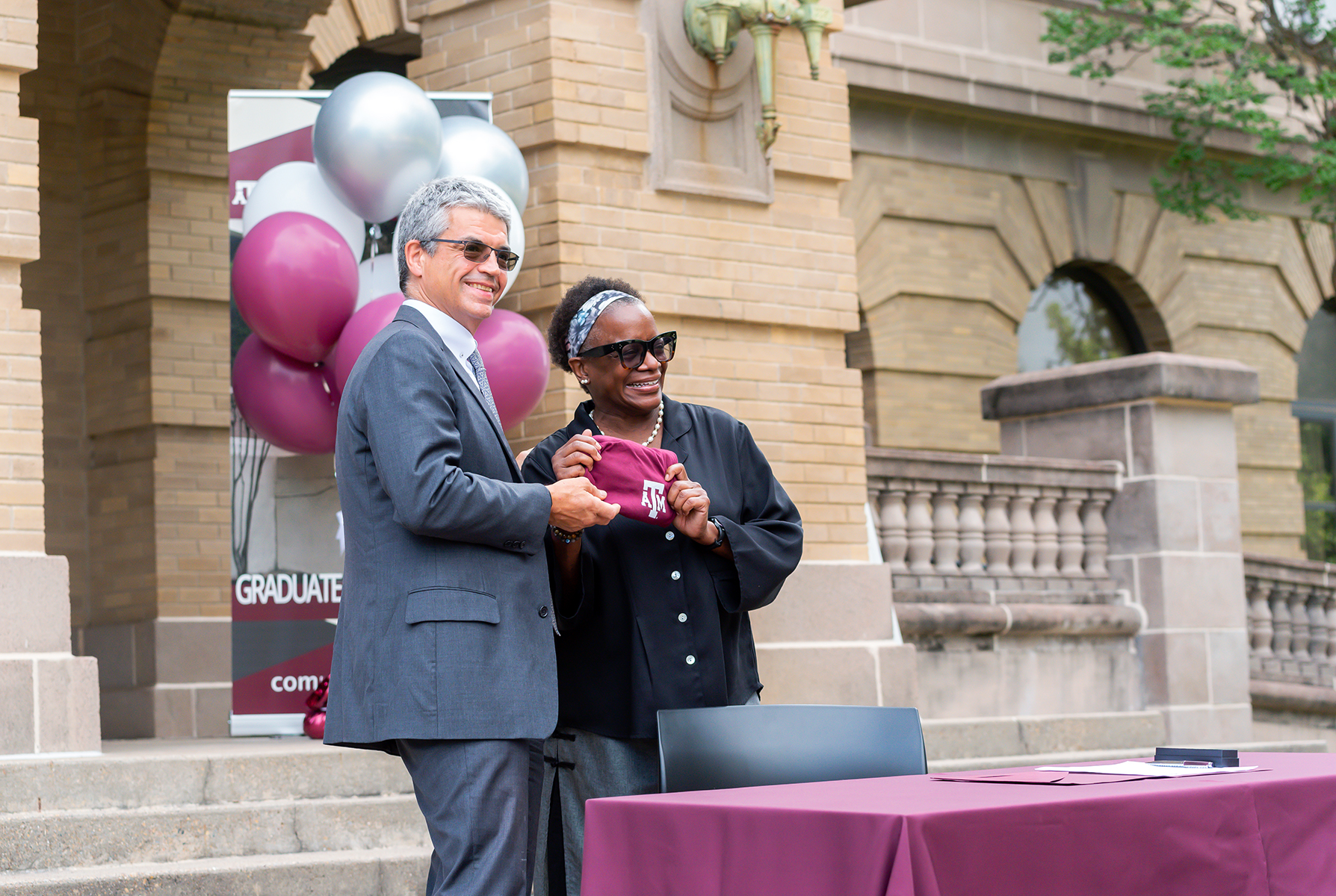 College of Arts and Sciences Interim Dean Dr. José Luis Bermúdez presents Dr. Kathleen McElroy with a Texas A&amp;M t-shirt during a signing ceremony outside the Academic Building unveiling her as director of the Texas A&amp;M Journalism Program