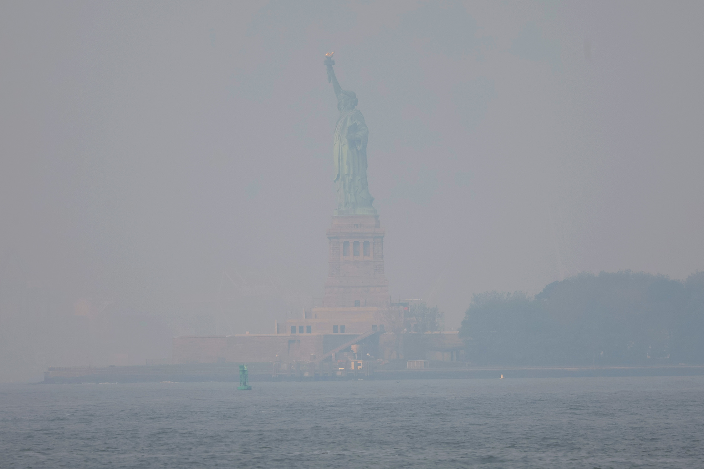 The Statue of Liberty, barely visible amid a New York skyline dominated by thick smoke caused by wildfires in Canada