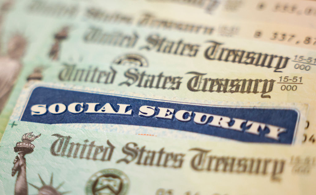 Close-up of a social security card in between a stack of United States Treasury notes