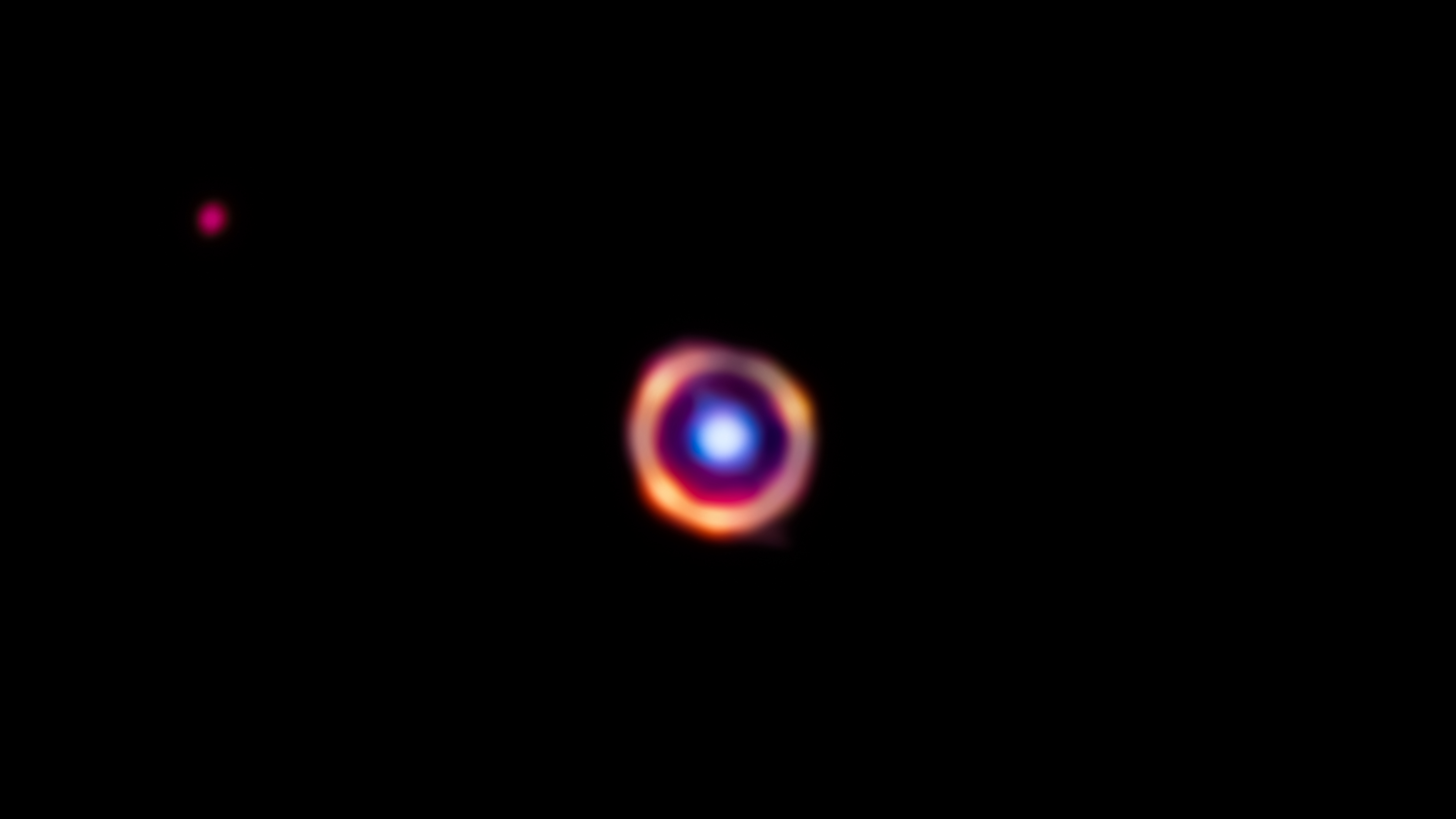 False-color James Webb Space Telescope image of an Einstein ring, composed of a foreground galaxy shown in blue and a background galaxy shown in red along with organic molecules that are highlighted in orange
