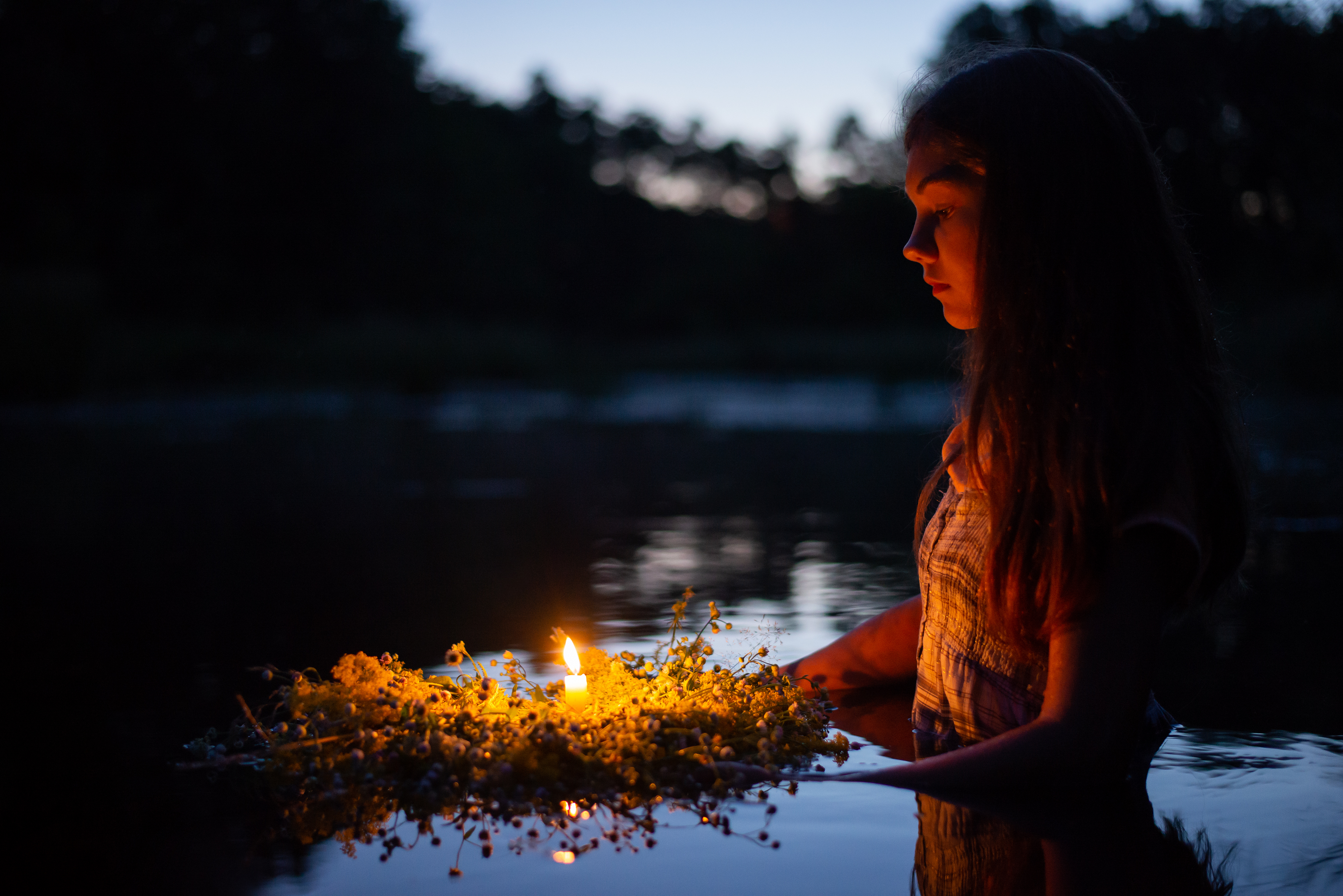 Portrait of a small girl in river late at night, set the wreath to float with a candle