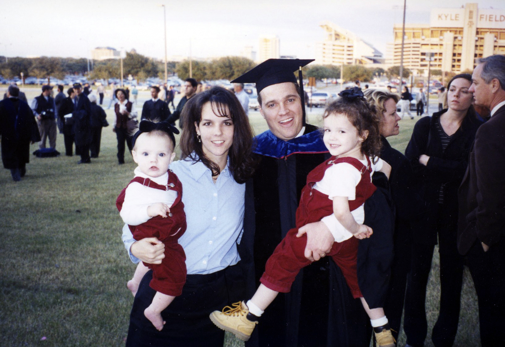 C. Shane Reese stands outside Reed Arena in his cap and gown, celebrating his 1999 graduation from Texas A&amp;M University with his wife and daughters