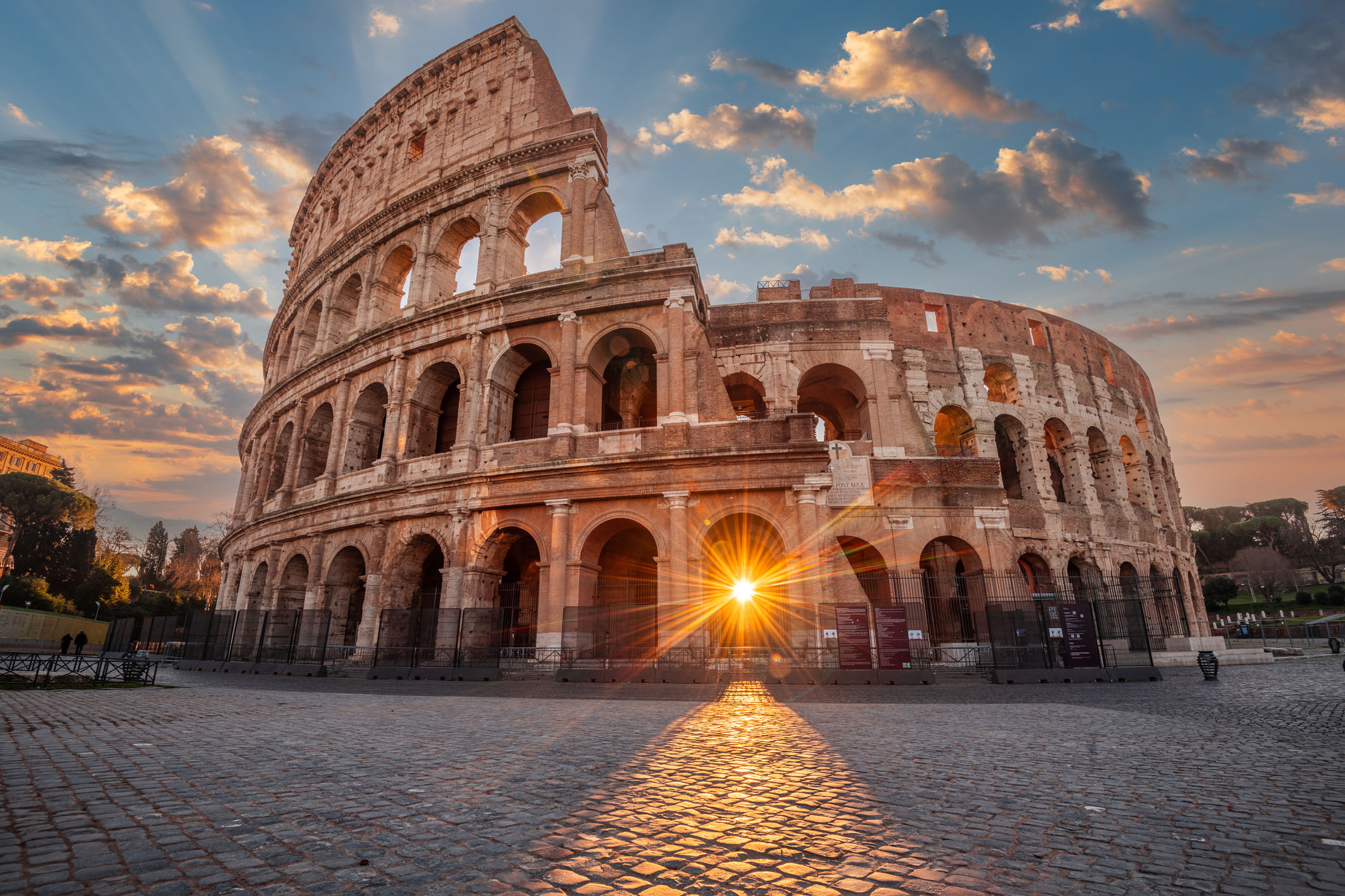 The Colosseum Amphitheater in Rome, Italy, with the sunrise visible through the entranceway