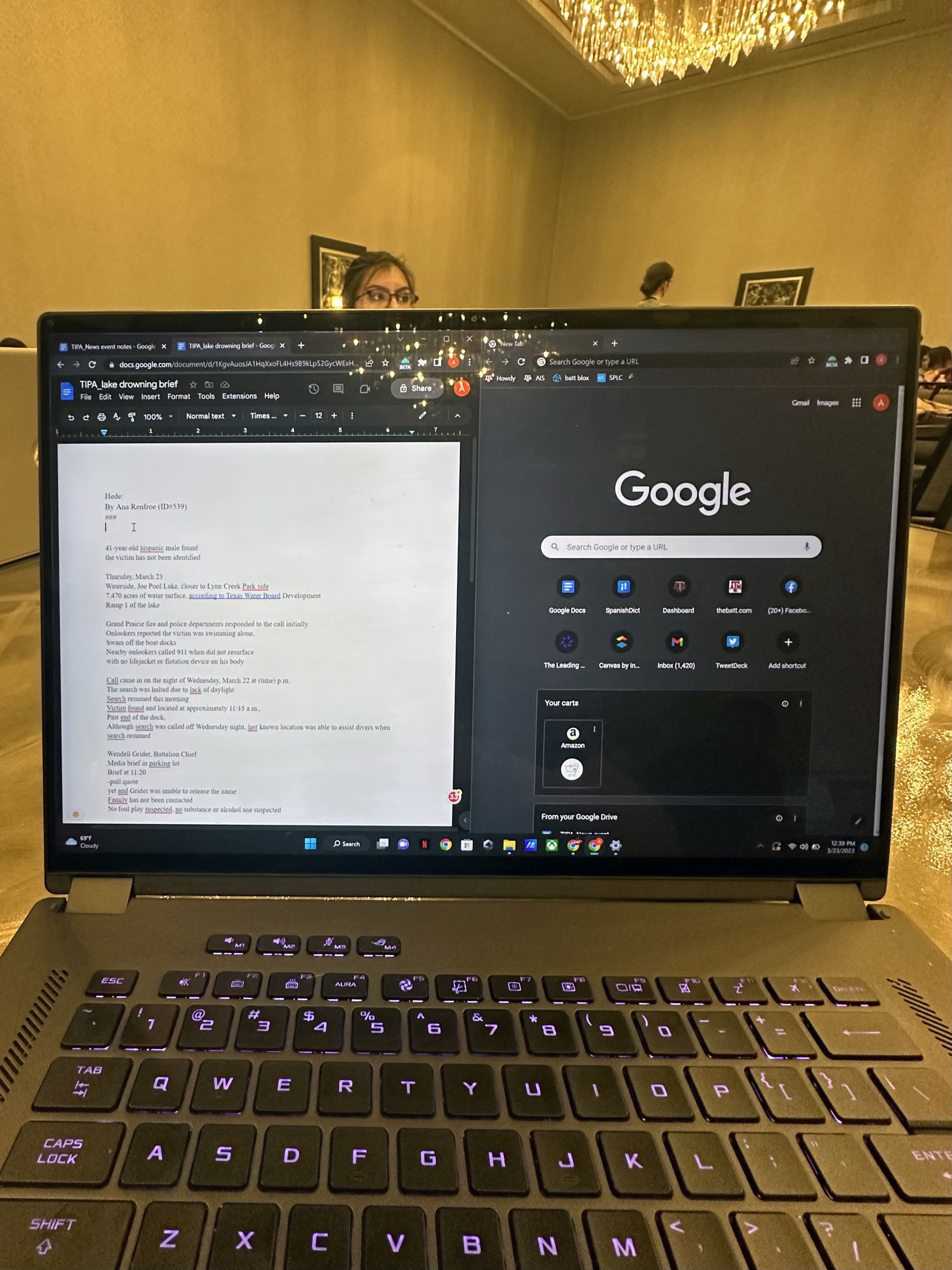 An open laptop with a writing application and internet browser open on the screen in a conference room