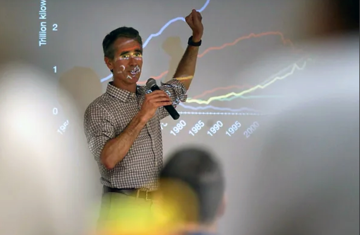 Wellesley College professor and author Jay Turner presents his research while standing in front of a projection screen