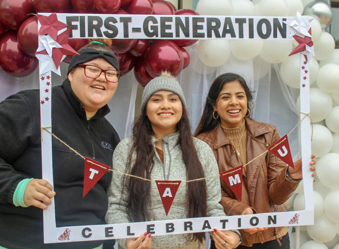 Three Texas A&amp;M University first-generation students pose inside a frame featuring the words "First-Generation Celebration" surrounded by maroon and white balloons