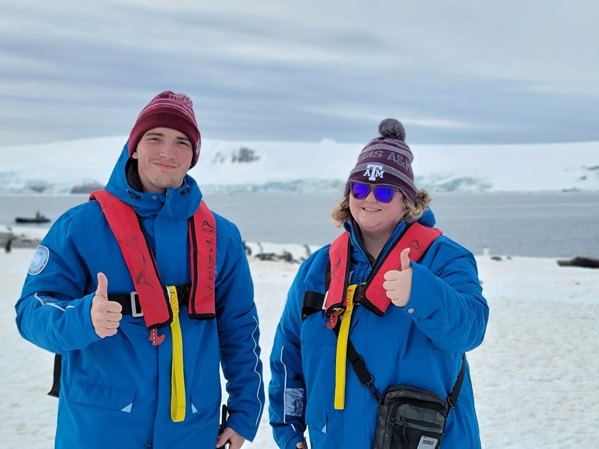 Two students participating in Texas A&amp;M University's first study abroad trip to Antarctica in late fall 2023 flash smiles and thumbs-up gig 'em signs for the camera
