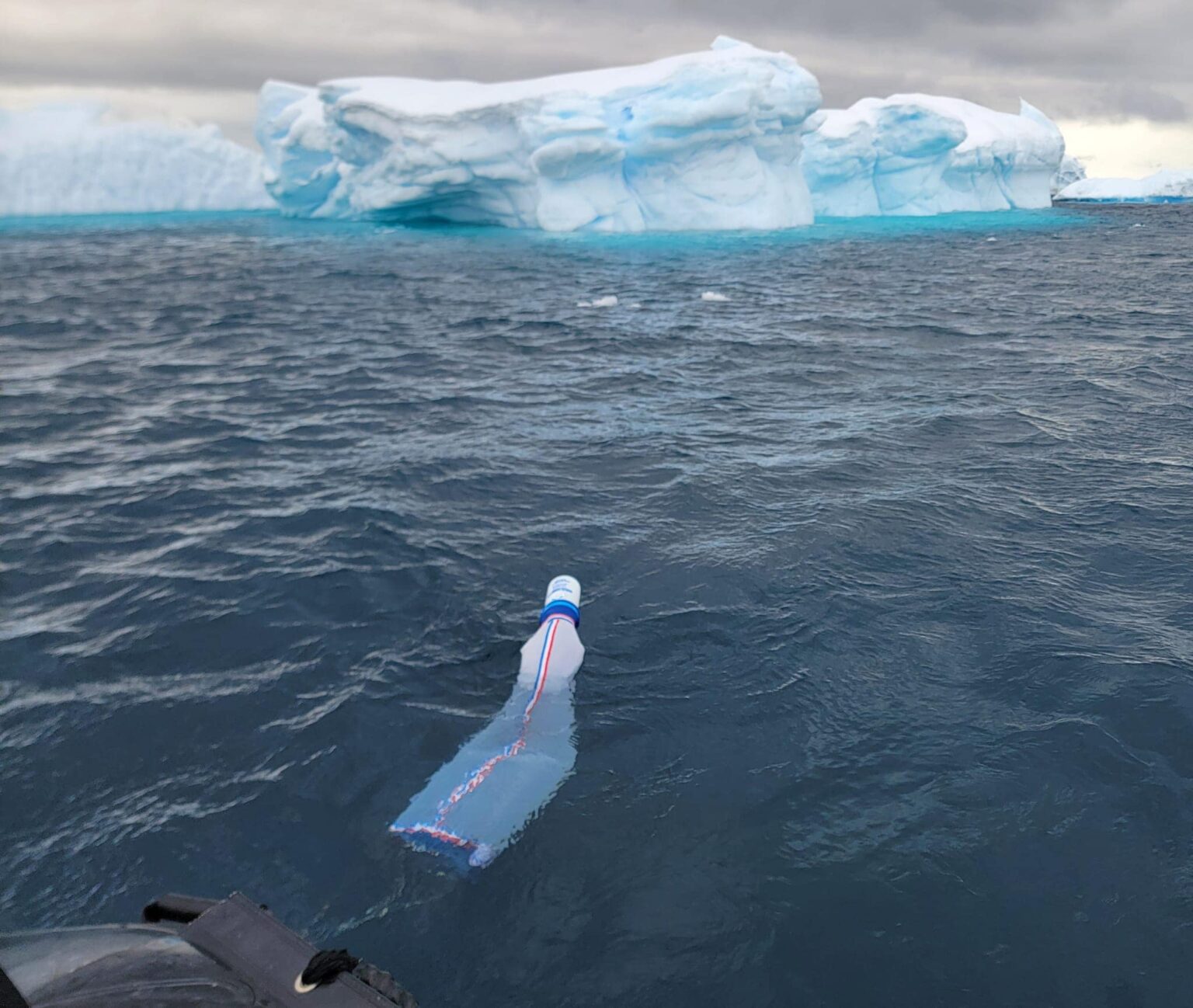 A bag collecting water samples floats while filling amid choppy seas with an iceberg in the background during Texas A&amp;M University's first study abroad trip to Antarctica in late fall 2023