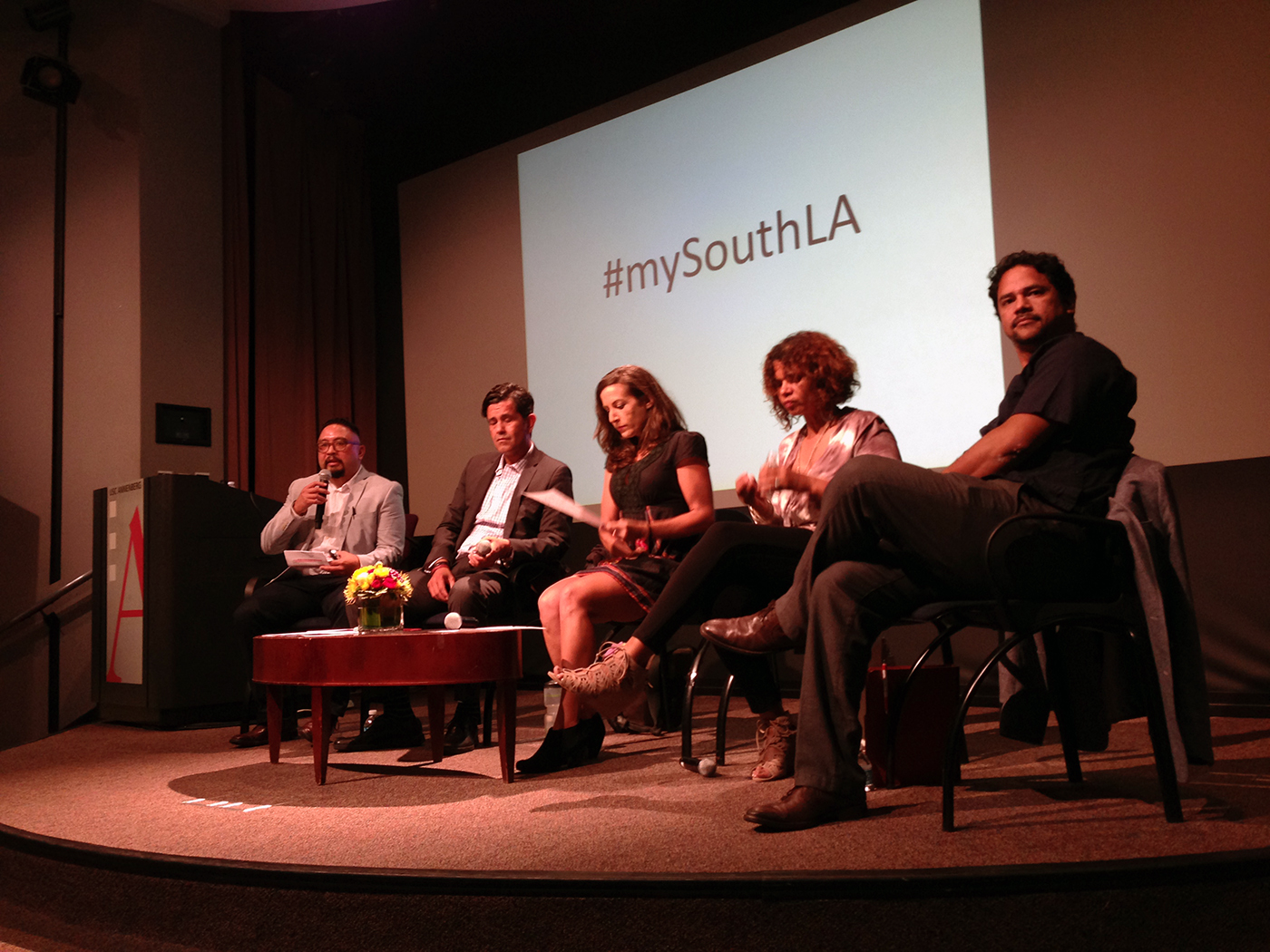 Texas A&amp;M University communication professor George Villanueva sits on a stage along with four other speakers while moderating a panel of South Los Angeles community leaders and media producers during an event on the University of Southern California campus