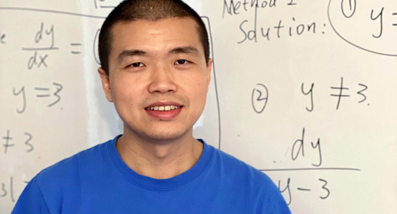 Texas A&M University mathematician Wencai Liu, standing in front of a white board filled with hand-written mathematical formulas
