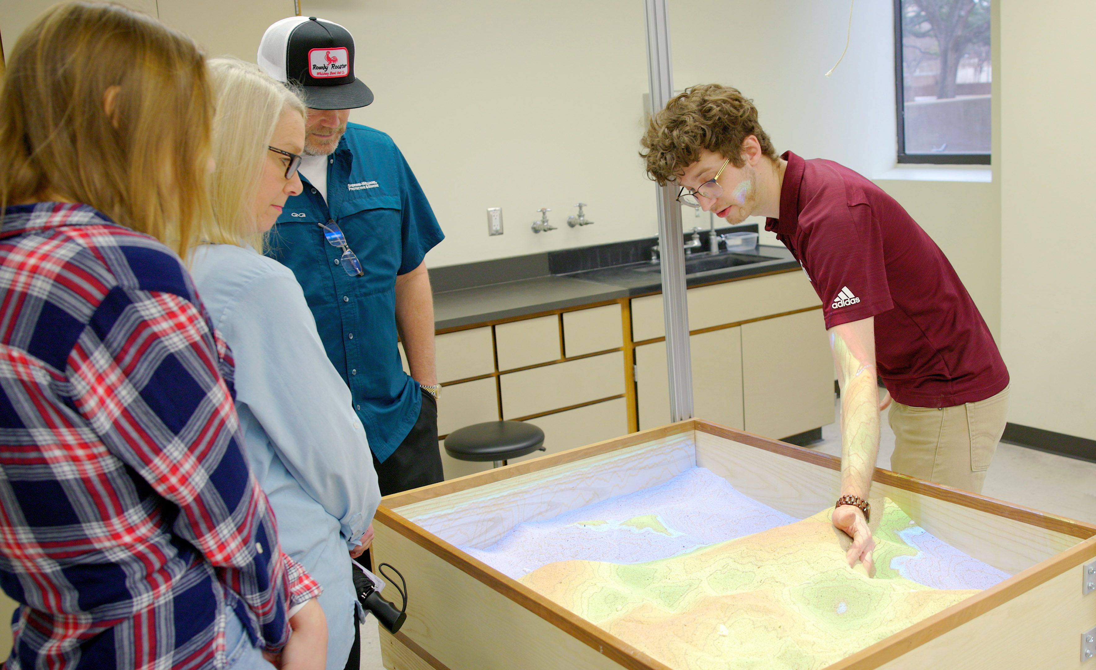 Texas A&amp;M University Geology and Geophysics graduate student Dirk van de Laar uses a sand table to illustrate a geological concept on Aggieland Saturday, held February 10, 2024