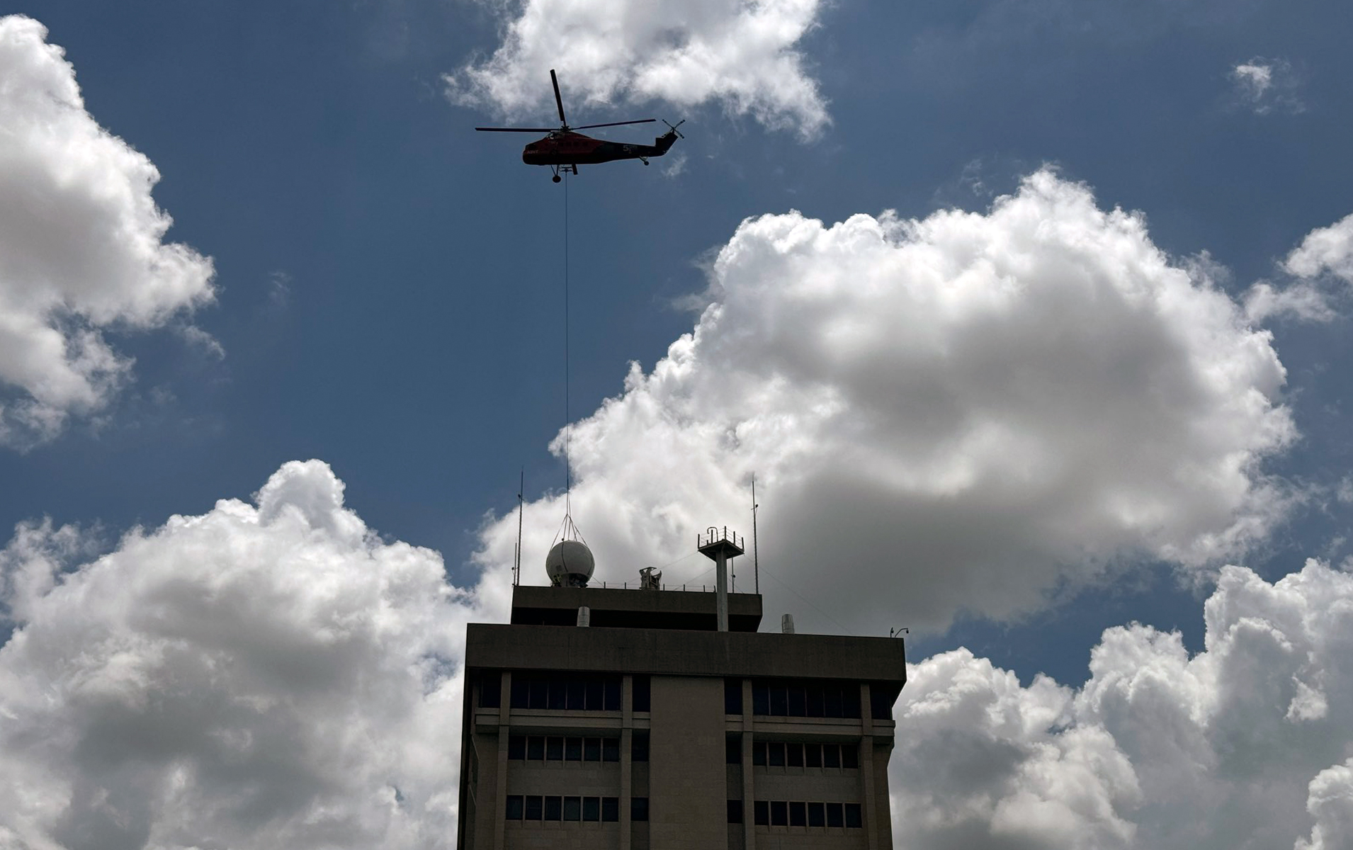 Skyline image of the top of the Eller Oceanography and Meteorology Building, showing the new weather radar system as it is placed via helicopter on June 22, 2024