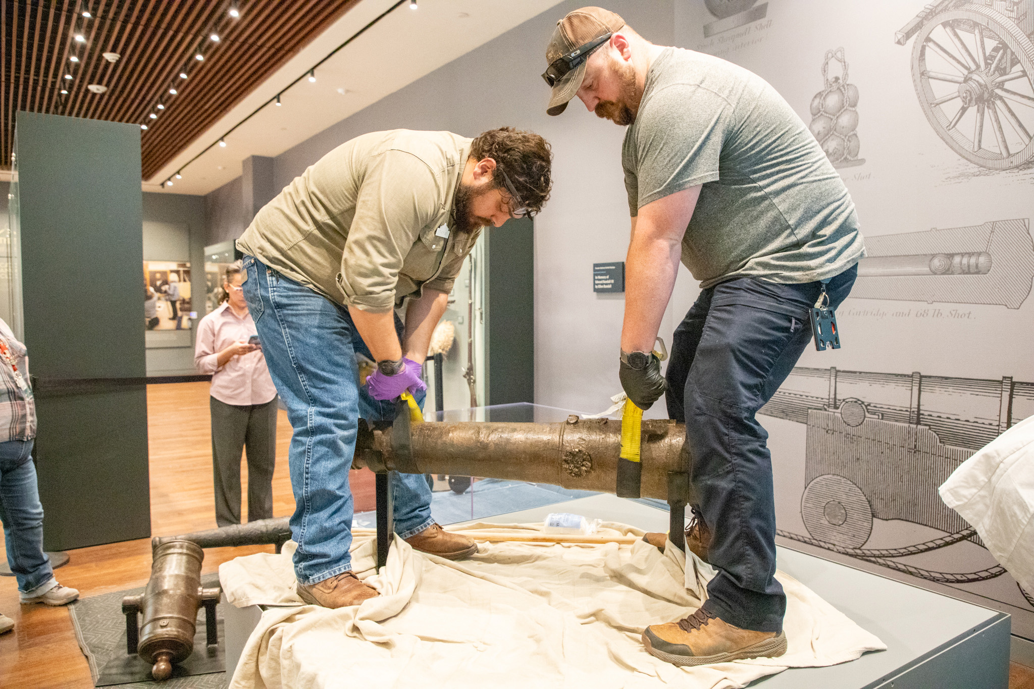 Two staff members adjust a four-pound bronze cannon used in the Battle of Alamo within the display area of the museum in San Antonio