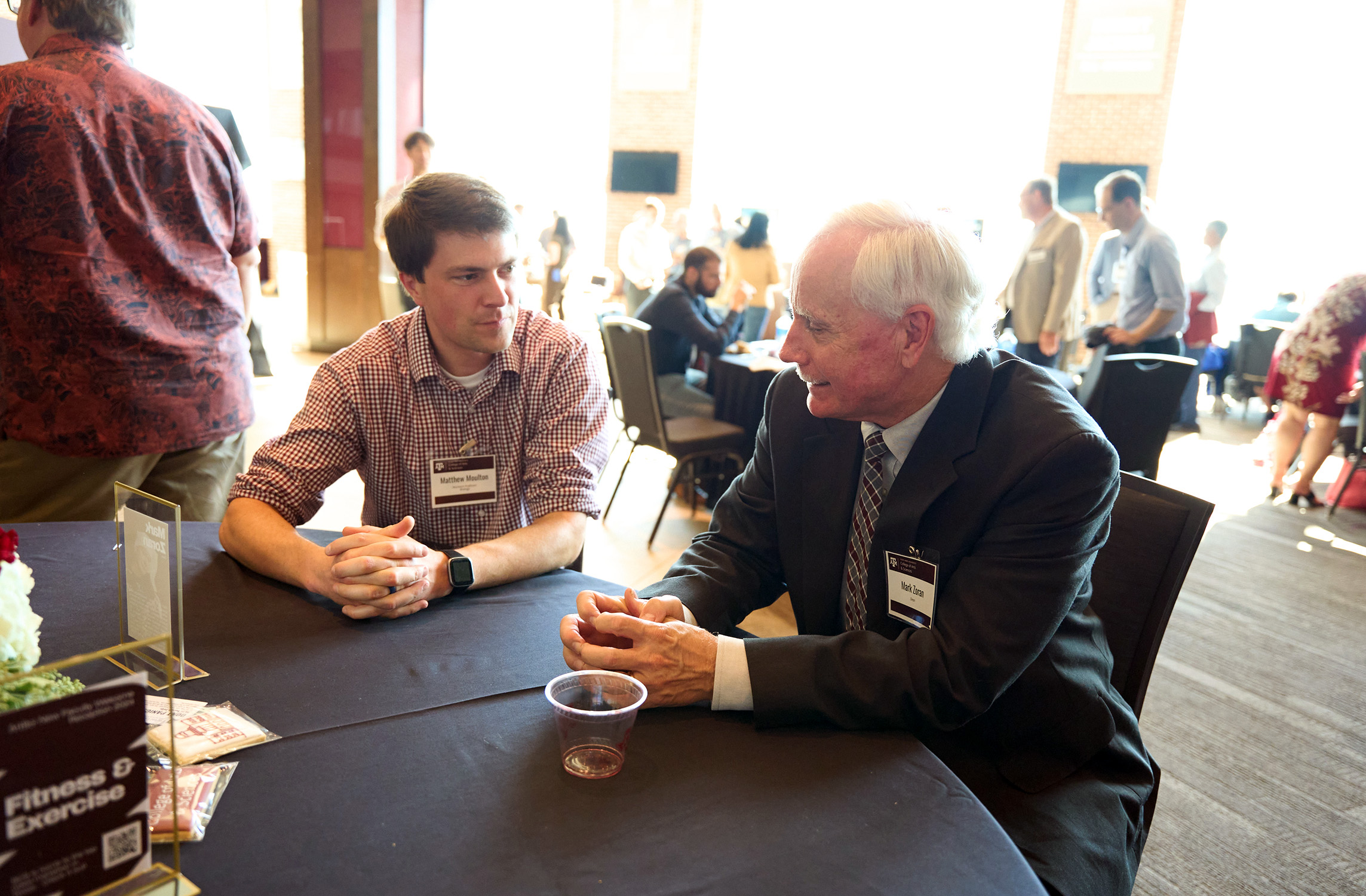 Texas A&amp;M University biologist and College of Arts and Sciences Dean Mark Zoran (right) sits at a table, talking with fellow Texas A&amp;M biologist Matthew Moulton