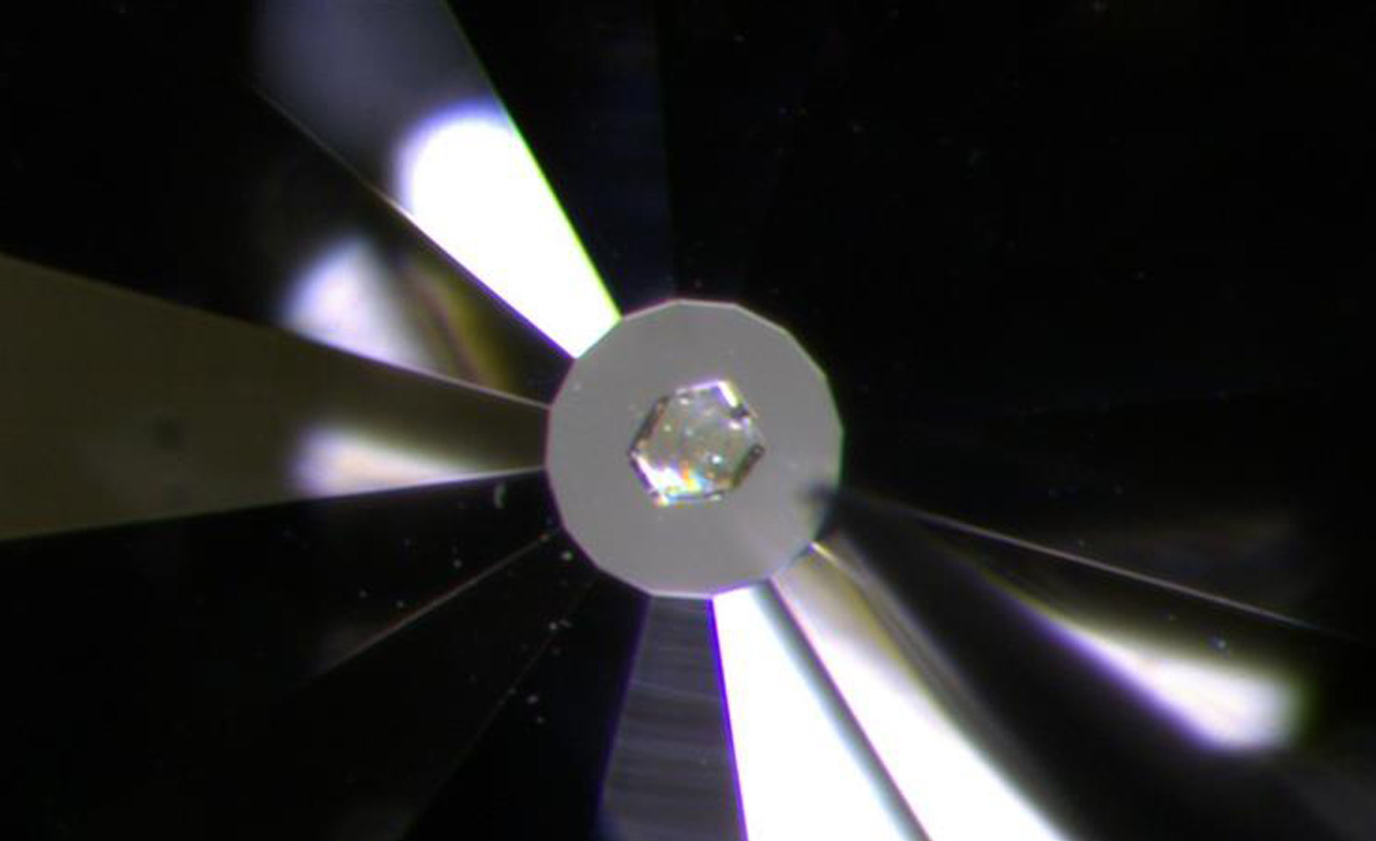 A close-up image of a diamond used to apply pressure to a crystal shown in the middle.